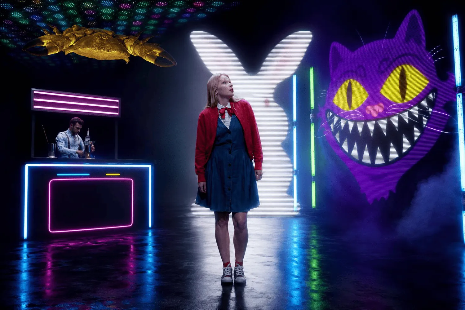 A performer on a neon-lit set with oversized cartoon characters